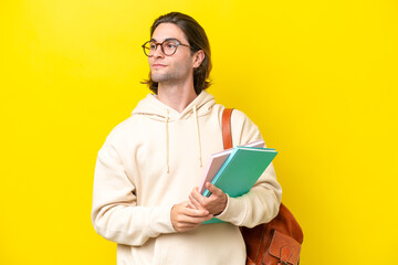 Young student handsome man isolated on yellow background looking to the side