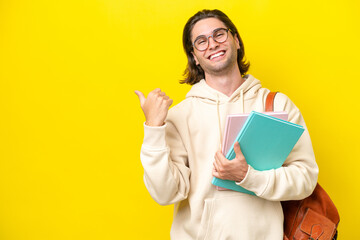 Young student handsome man isolated on yellow background pointing to the side to present a product