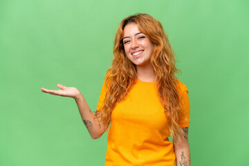 Young caucasian woman isolated on green screen chroma key background holding copyspace imaginary on the palm to insert an ad
