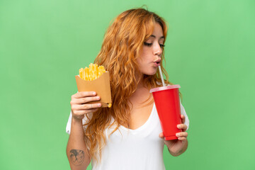 Young caucasian woman holding fried chips and soda isolated on green screen chroma key background  background