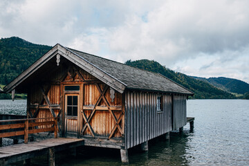 wooden boat house in lake in front of forest trees