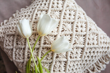 White pillows with macrame. Bed in a minimal bedroom scandinavian style. White tulip on macrame pillow