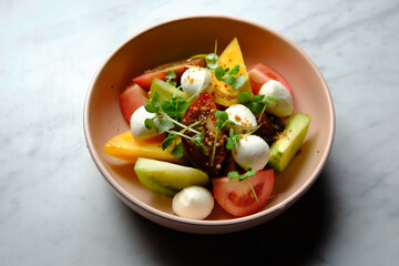 Heirloom tomatoes salad with mozzarella cheese in a pink bowl