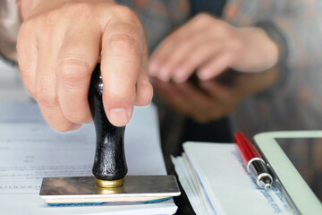 hand holding rubber stamper on white paperwork