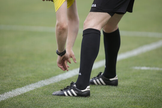 Details with a football (soccer) referee stretching before a game.