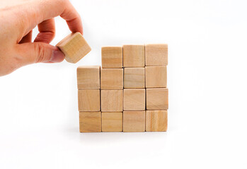 Obraz premium hand pick a wooden cube from stack on white background