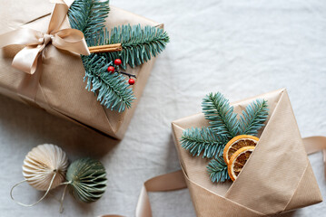 Beautifully wrapped Christmas gifts with natural decor on the top lie on the table.