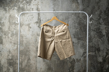 Men's beige shorts hang on a clothes rack.