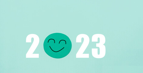 2023 with smiley face paper cutout, positive mental health, personal satisfaction goal, green background
