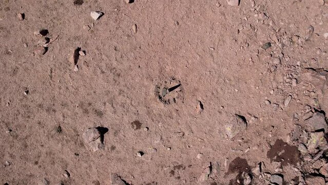 Drone view of a sundial made of stones. The shadow from the sun shows what time it is now. There are large stones lying around, moss grows in places. Sandy pass in the mountains. Kazakhstan