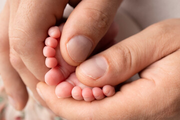 Mother and father are doing massage on her baby foot. Closeup baby feet in mother hands. Prevention of flat feet, development, muscle tone, dysplasia. Family, love, care, and health concepts.