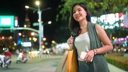 Obraz premium Attractive asian woman traveler waiting for cab for transporting in megalopolis on avenue. Tourism and transportation concept