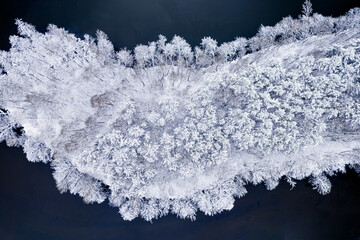 Cold river and snowy frozen forest. Aerial view of winter.
