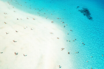 Top view of beautiful seascape. Aerial view of the white sand beach and swimming people in transparent blue water. Sardinia, Italy