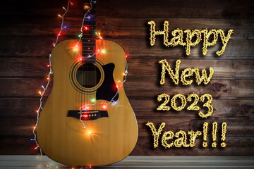 Acoustic guitar in a New Year's garland, a guitar in a garland under a wooden wall, copy space,...