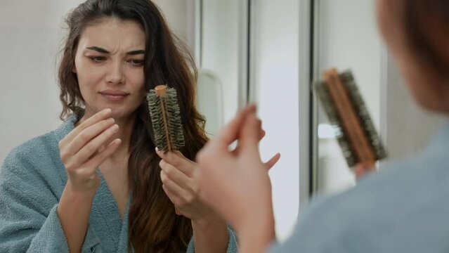 Woman losing hair on hairbrush in hand