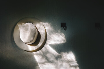 White hat hanging on the wall in the morning light.