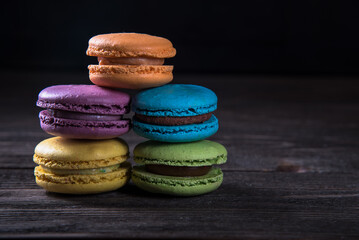 Macaroon cakes on wooden table and dark background