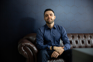 young businessman sitting on sofa looking forward