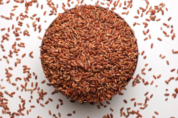 Dry Rice in wooden Bowl. Long Brown Rice Rotating. Close Up. Grains fall poured a stack. World crisis, export, import. Harvest problems, sanctions. Increase prices and shortages of food supplies
