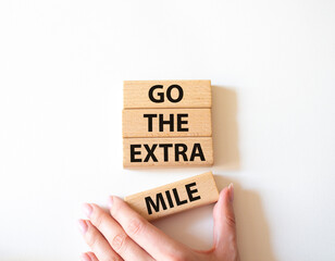 Go the extra mile symbol. Wooden blocks with words Go the extra mile. Beautiful white background. Businessman hand. Business and Go the extra mile concept. Copy space.