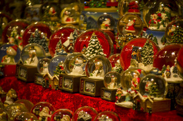 Advent Bazaar Stalls with glass, wooden, ceramic christmas souvenirs in shops. Close up of festive decorations for tree in winter street night market during new year's holiday. Illuminated fair kiosk