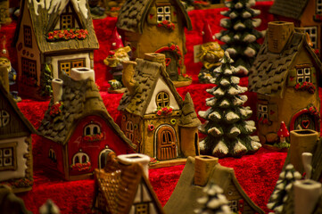 Fototapeta premium Advent Bazaar Stalls with glass, wooden, ceramic christmas souvenirs in a shop. Close up of festive decorations for tree in winter street night market during new year's holiday. Illuminated fair kiosk