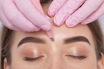 Makeup artist plucks eyebrows after dyeing in a beauty salon. Professional make-up and cosmetic...