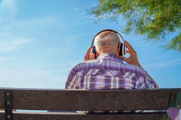 elderly man listening to music backwards sitting on a bench