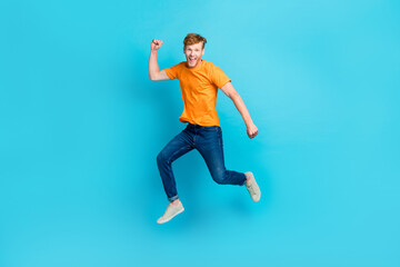 Fototapeta na wymiar Full length photo of hooray ginger hair guy jump wear t-shirt jeans sneakers isolated on blue color background