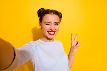 Photo of funky adorable lady wear long sleeve recording self video winking showing v-sign isolated yellow color background