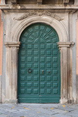 Italian door in green wood with decorated rock portal