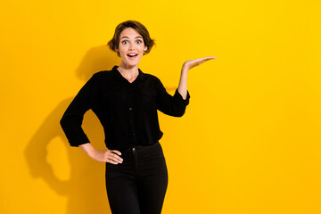 Photo of impressed millennial short hair lady hold promo wear black shirt jeans isolated on yellow color background