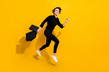 Fototapeta na wymiar Photo of sweet charming girl dressed formal shirt jumping high holding bags running empty space isolated yellow color background