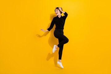 Fototapeta na wymiar Photo of dreamy charming girl dressed formal shirt jumping high looking empty space isolated yellow color background