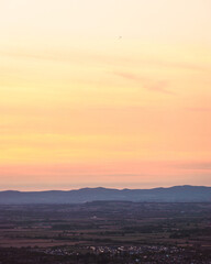 Flock of birds fly towards the Malvern Hills from Cleeve Common in Gloucestershire at sunset.