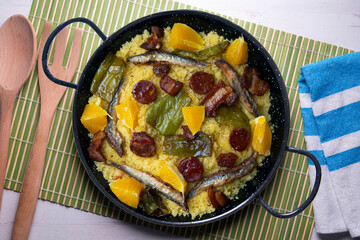Migas with chorizo, sardines, bacon and green peppers cooked in a black paella. Typical Spanish tapa recipe.