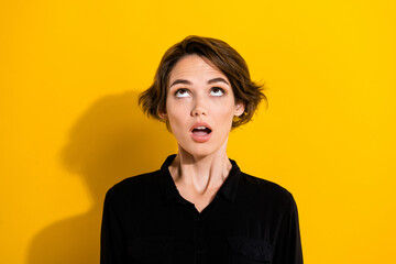 Photo of amazed young short hair lady look up wear black shirt isolated on yellow color background