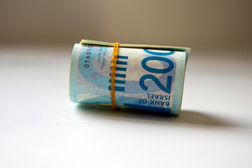 A bunch of Israeli New Shekels (NIS) money notes rolled up and held together with a simple rubber...