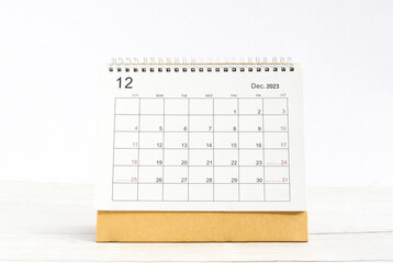 december 2023 Desktop calendar for planners and reminders on a wooden table on a white background.