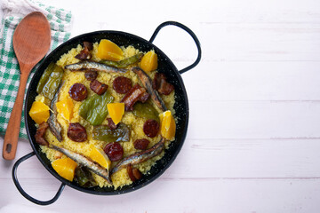 Migas with chorizo, sardines, bacon and green peppers cooked in a black paella. Typical Spanish tapa recipe.
