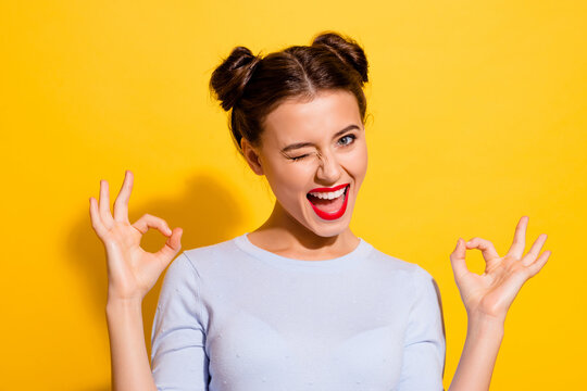 Photo of pretty attractive female flirty winking her eye showing okay symbol isolated on yellow color background