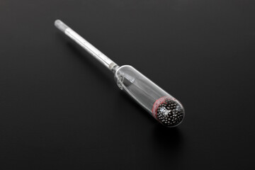 hydrometer, a tool for measuring the density of the battery electrolyte, on a black background