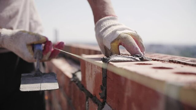 bricklayer lays red brick, masonry wall