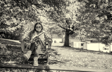 Woman relaxing on a big chair in a park, autumn season