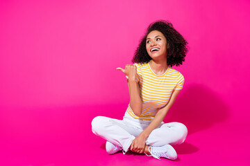 Full length photo of young adorable pretty girl wear striped t-shirt finger pointing empty space interested look isolated on pink color background