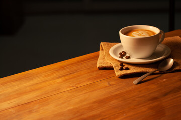 Café au lait dans une tasse en porcelaine avec serviette et grains de café sur planche de bois. Café au lait dans une tasse en porcelaine avec serviette et grains de café sur planche de bois.