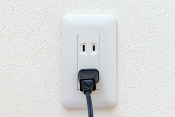 部屋の壁のコンセントに接続された電源プラグ