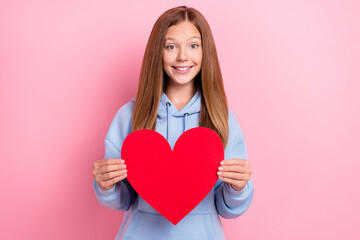 Portrait photo of young funny little cute excited positive toothy smile girl hold red paper heart showing feelings first date isolated on bright pink color background