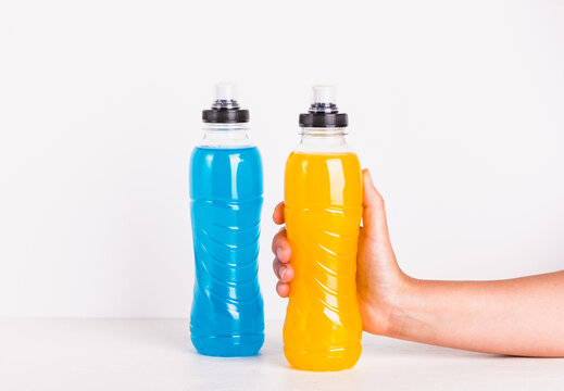 Isotonic sport water energy drink copy space white background. Woman hand hold bottle with yellow hydration sport beverage.	